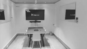 Meeting room with AV design and large TV screen showing iwGROUP logo