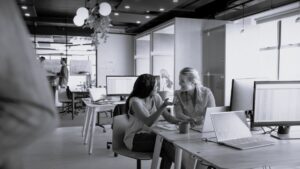 Two female colleagues working together in open plan office